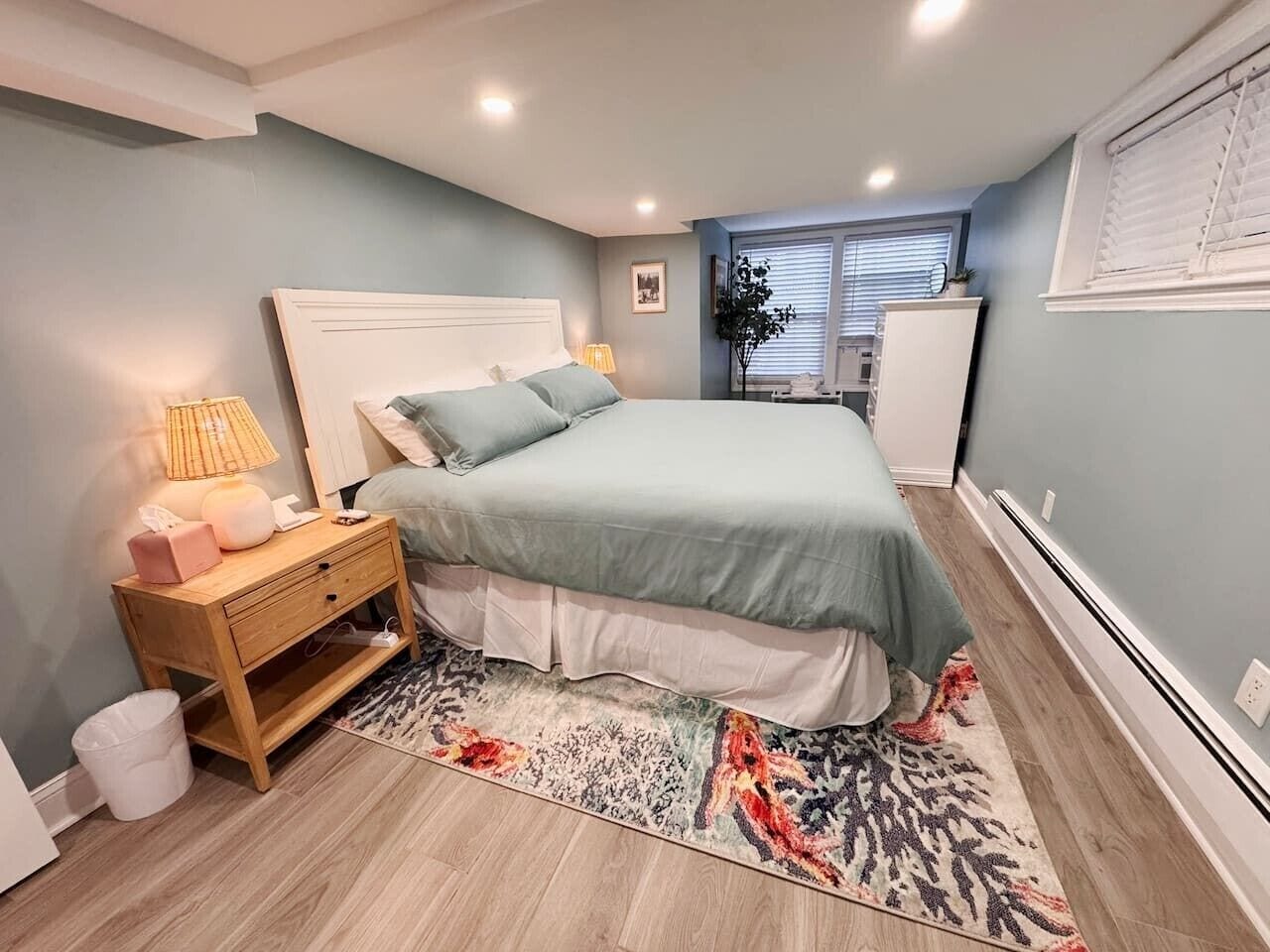 A bedroom with a bed, bedside table, lamp, and a rug.