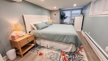 A bedroom with a bed, bedside table, lamp, and a rug.