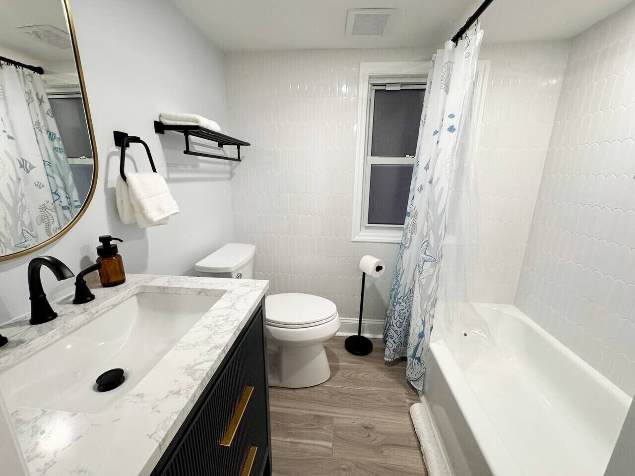 A bathroom with a sink, toilet, bathtub, and a window with a curtain.