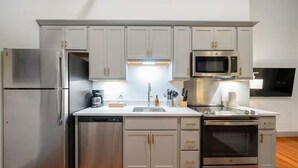 Una cocina moderna con electrodomésticos de acero inoxidable, armarios blancos y suelo de madera.