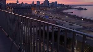 A cityscape at dusk with a waterfront promenade, high-rise buildings, and a bridge. - Charming Mar del Plata Apartment With Ocean Views (Mar del Plata)