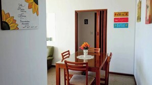A dining area with a wooden table and chairs, a vase with flowers, and a wall with a welcome sign and a 'Happy Birthday' sign. - Charming Mar del Plata Apartment With Ocean Views (Mar del Plata)