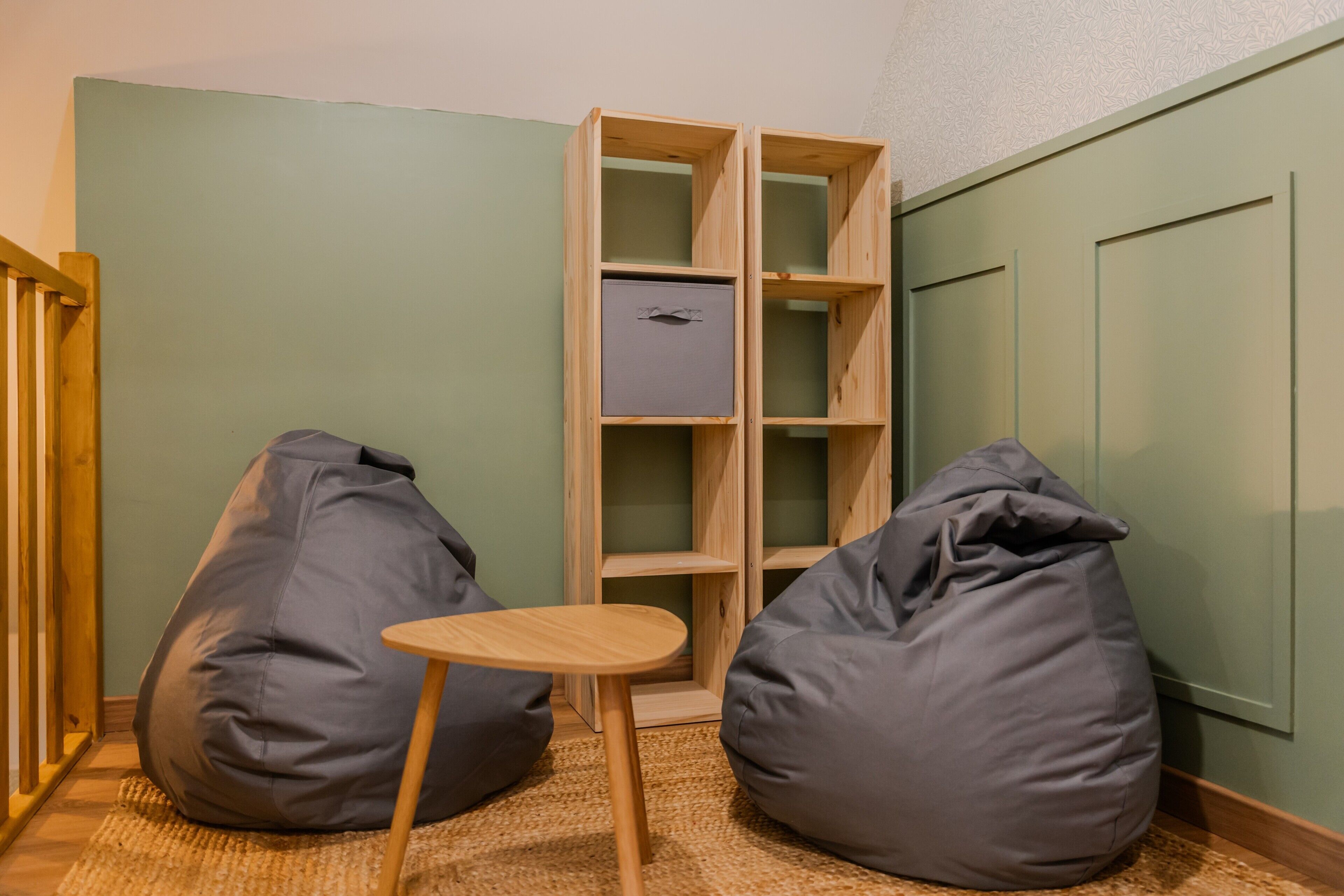 Una habitación con dos sillones de mimbre, una pequeña mesa de madera y una estantería empotrada.