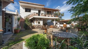 Un bâtiment à deux étages doté d’un patio aménagé avec du mobilier d’extérieur et des plantes.