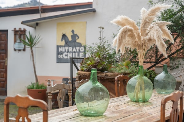 A rustic wooden table with three green glass bottles and pampas grass.
