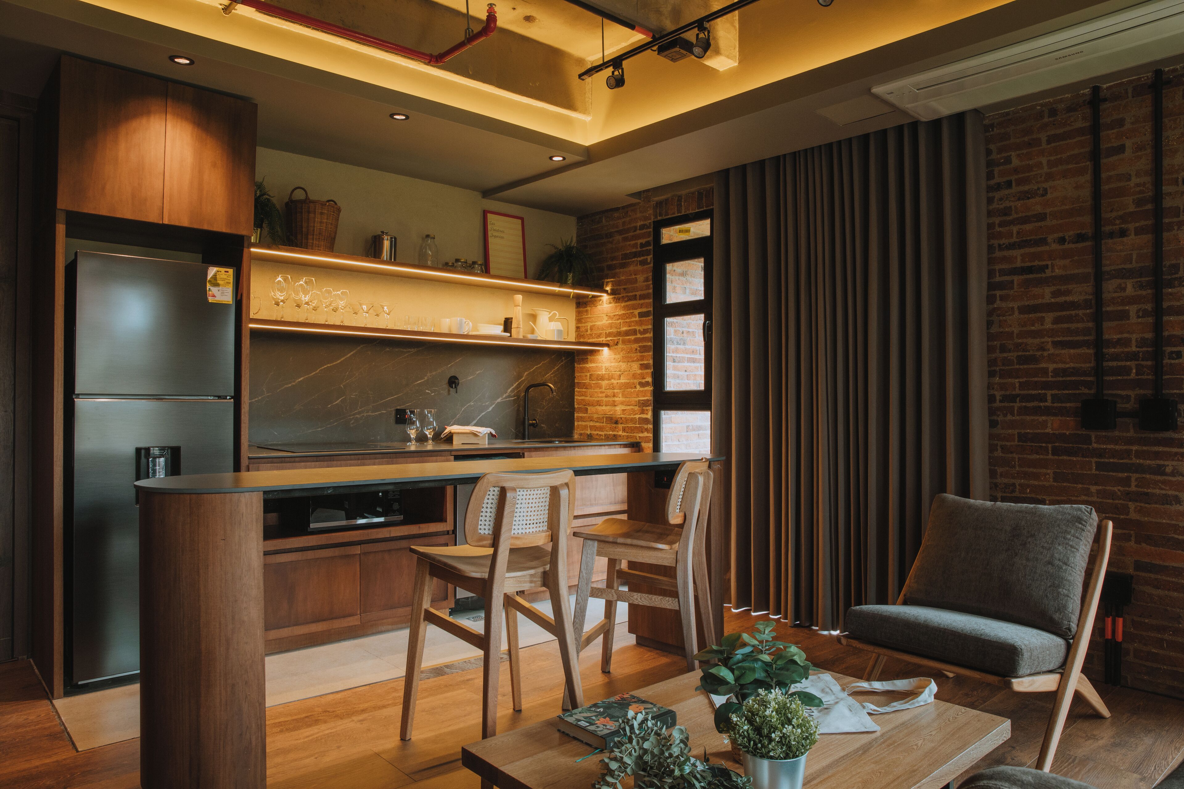 A modern kitchen with wooden cabinets, a built-in fridge, and a dining area with wooden chairs and a table.