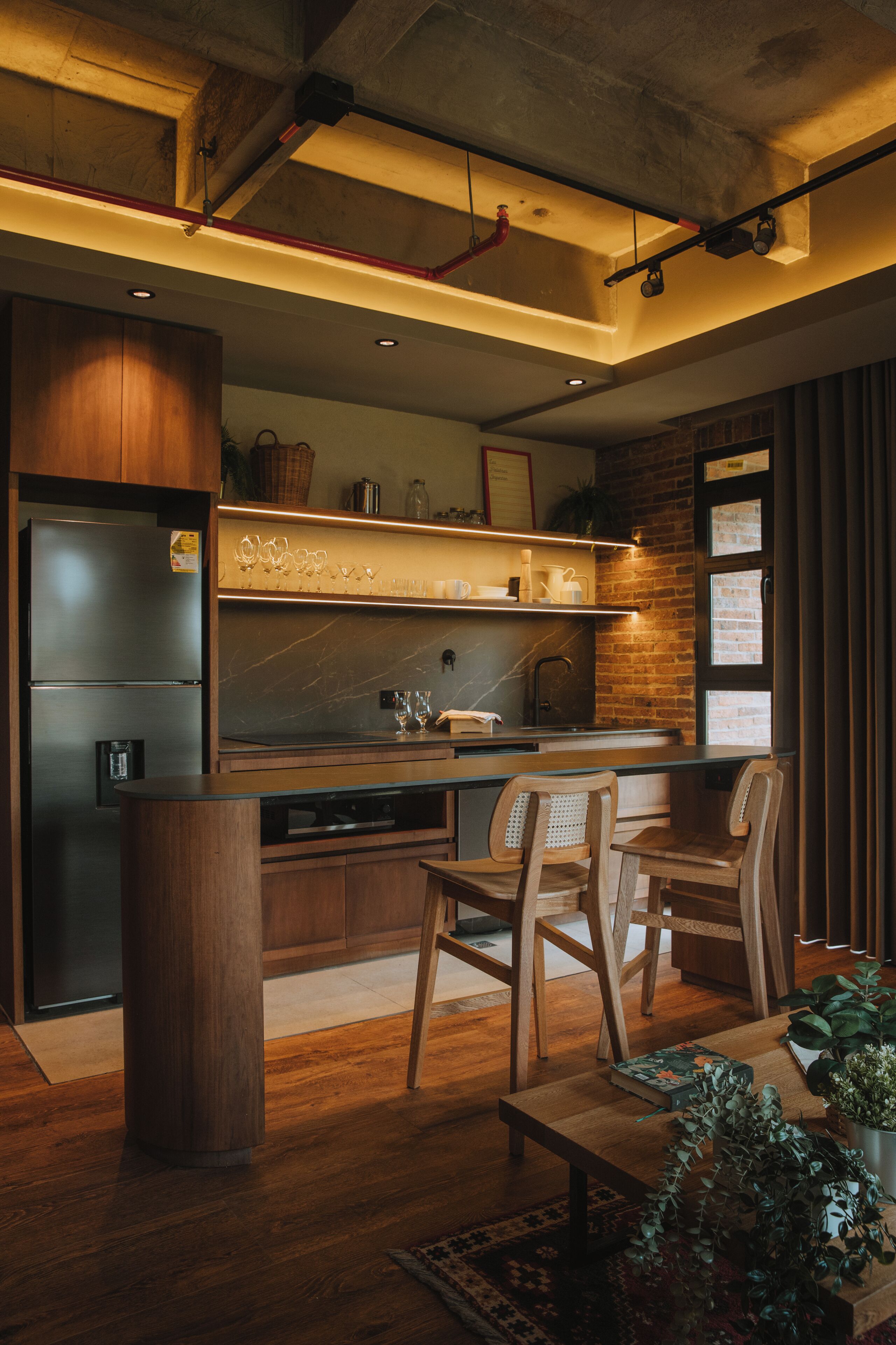 A modern kitchen with a built-in refrigerator, wooden cabinets, and a dining area with a table and chairs.