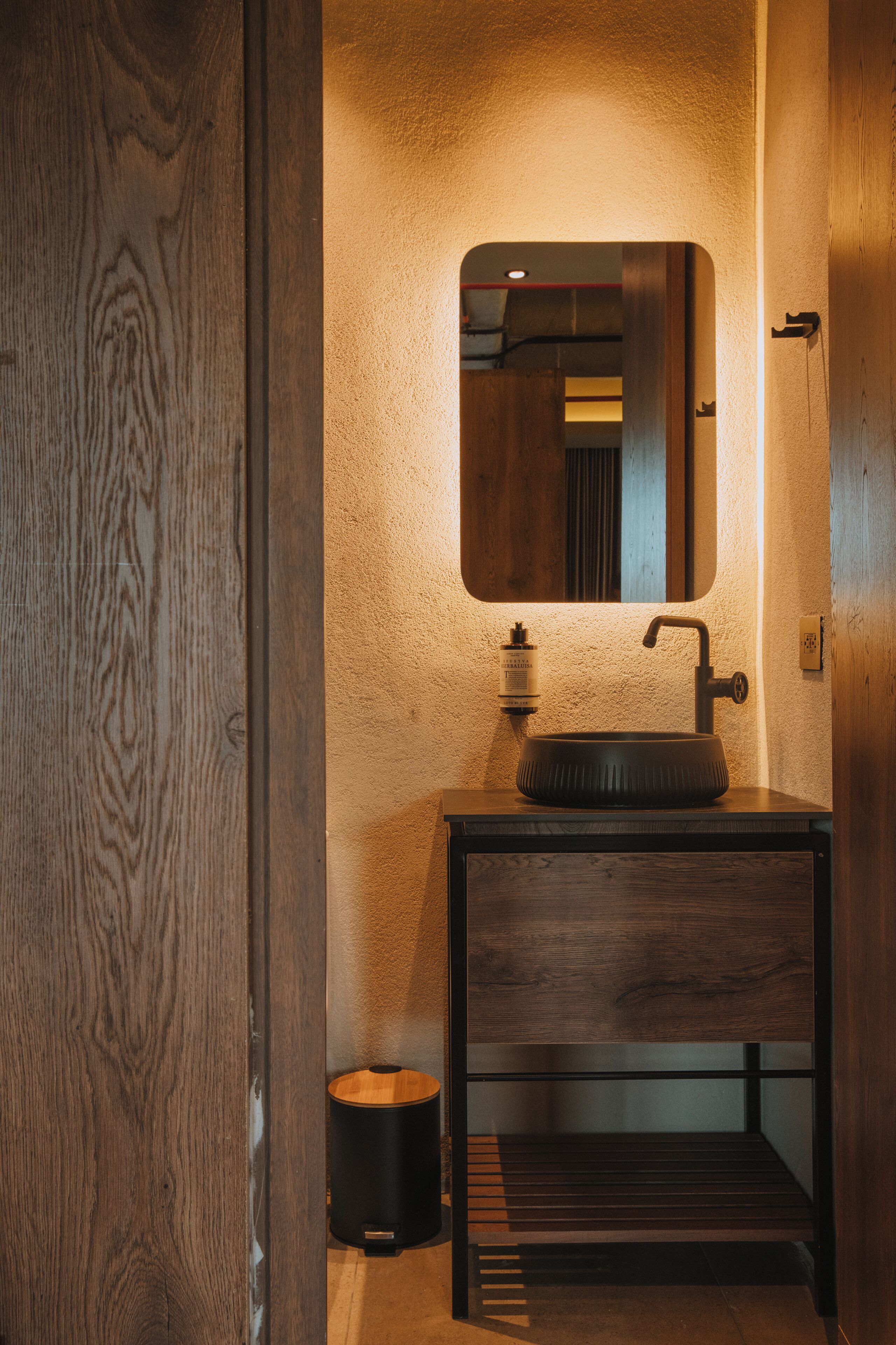 Une salle de bain avec un meuble-lavabo en bois, un lavabo rond et un miroir au-dessus.