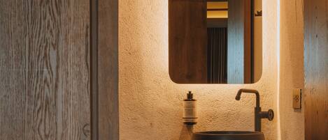A bathroom with a wooden vanity, a round sink, and a mirror above it.