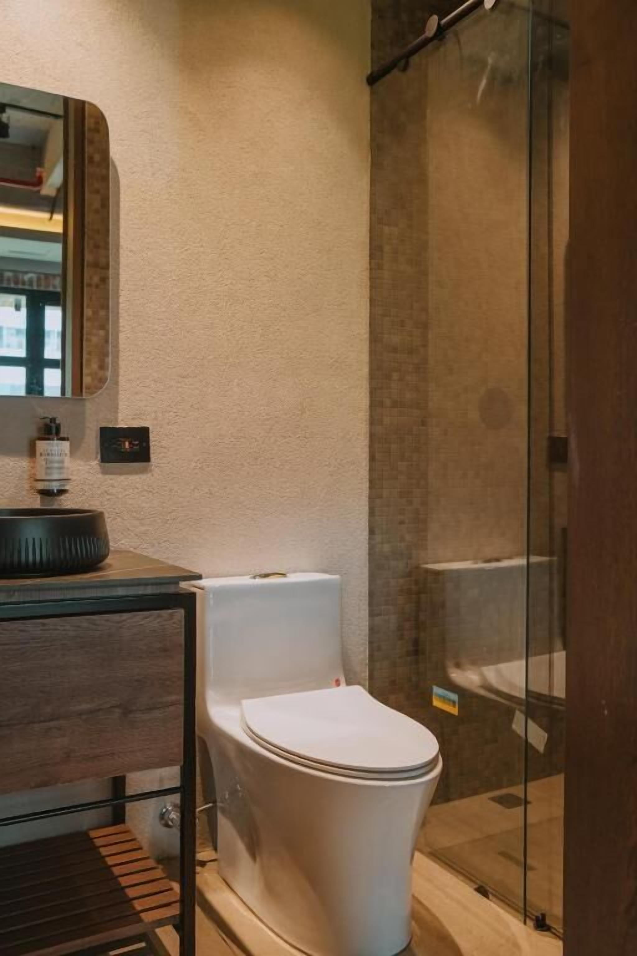 A modern bathroom with a white toilet, a glass shower enclosure, and a wooden vanity.