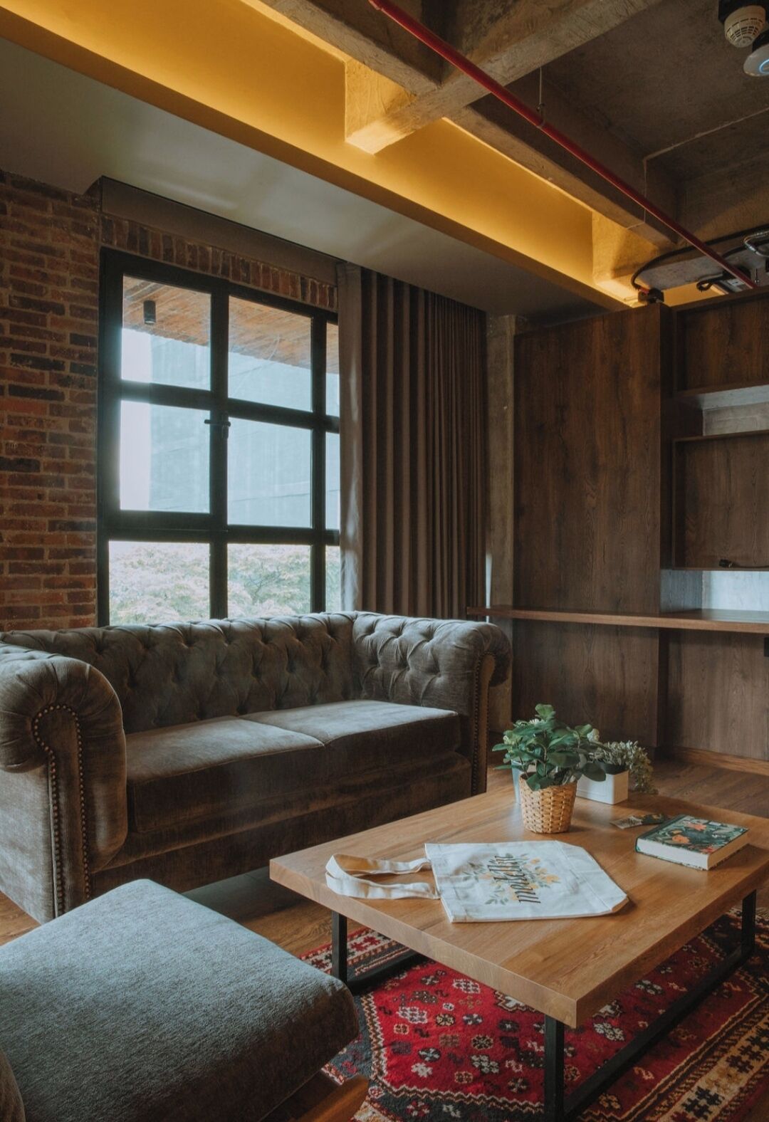 A cozy room with a leather sofa, a wooden table, and a brick wall.