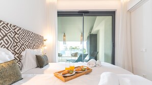 Habitación de hotel con una cama, una bandeja con croissants y jugo de naranja, y vista al exterior.