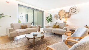 Una sala moderna con dos sofás, una mesa de centro y una silla. Hay platos decorativos en la pared y una planta.