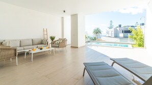 Amplia sala de estar con sofá, mesa de centro y sillones, con vista a una piscina y al paisaje circundante.