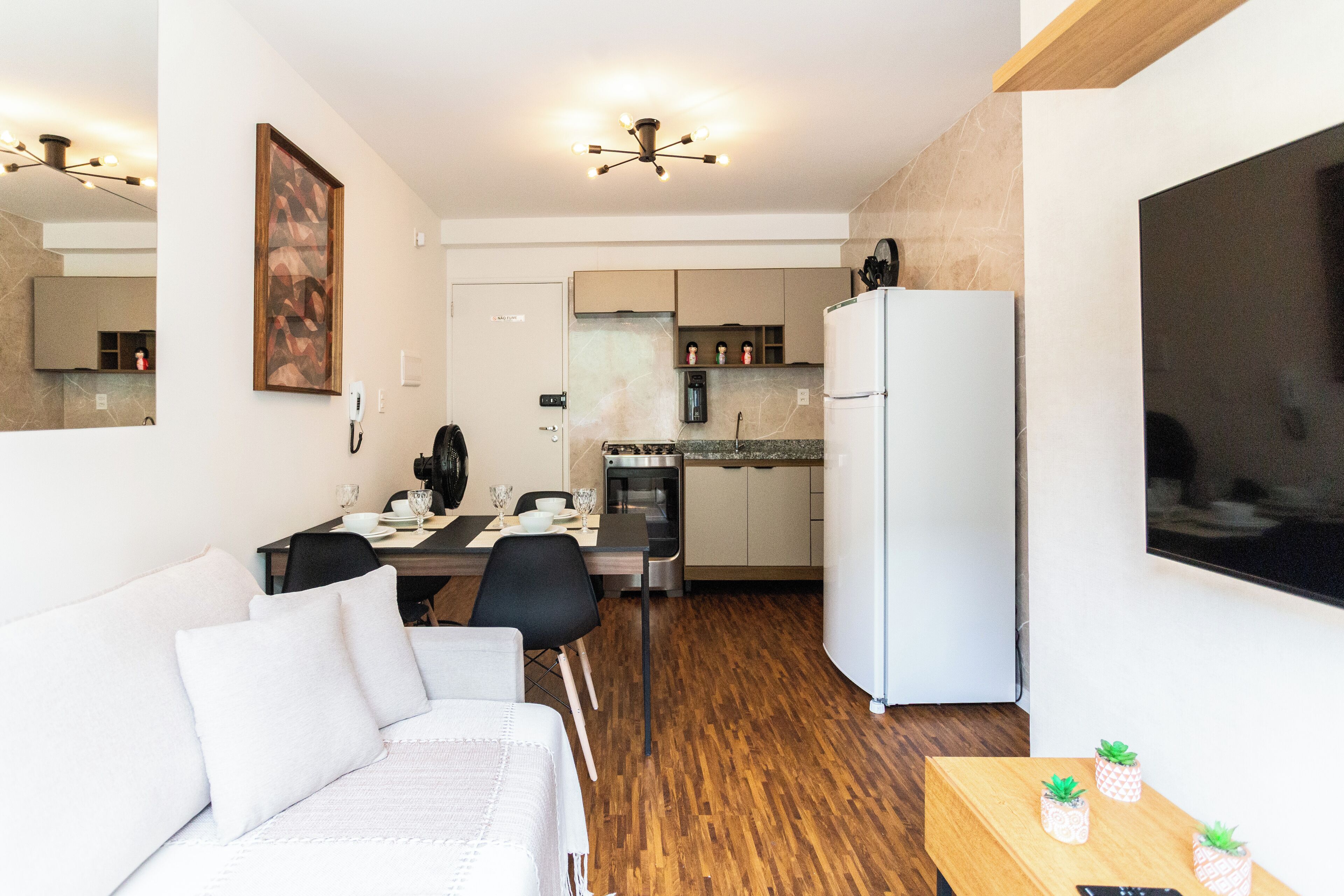 Uma sala de estar moderna com sofá, mesa de jantar e área de cozinha.