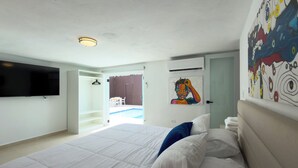 Ein Schlafzimmer mit einem großen Bett, einem flachbildfernseher an der Wand und einem Gemälde über dem Bett.