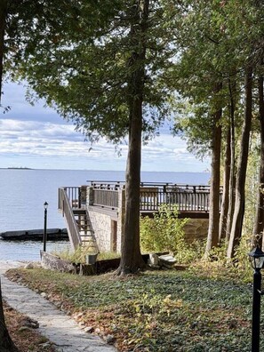 A wooden deck with a stone wall, overlooking a body of water.