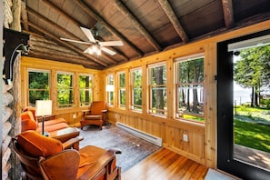 Une cabane en bois avec un ventilateur de plafond, de grandes fenêtres et une vue sur l’extérieur.