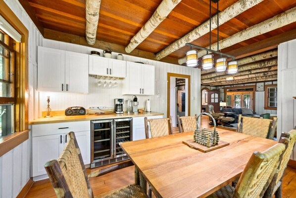 A rustic kitchen with white cabinets, a wooden dining table, and a built-in oven. - Sister Bay Waterfront Cabin with kayaks, boathouse deck, and game room! (Sister Bay)
