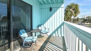 A balcony with a glass door, two chairs, and a small table.