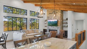 A spacious kitchen with a large island, a stone fireplace, and a TV mounted on the wall. - This is The Life - stunning mountain and lake view (Glenville)