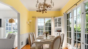 A dining area with a white table set for six, surrounded by wooden chairs with cushioned seats. - Chateau Beachwood (Los Angeles)