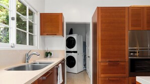 A modern kitchen with wooden cabinets, a stainless steel sink, and a built-in oven. - Chateau Beachwood (Los Angeles)