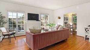A spacious living room with a large window, a fireplace, and a dining area. - Chateau Beachwood (Los Angeles)