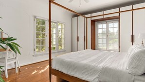 A bedroom with a wooden bed, white walls, and large windows. - Chateau Beachwood (Los Angeles)