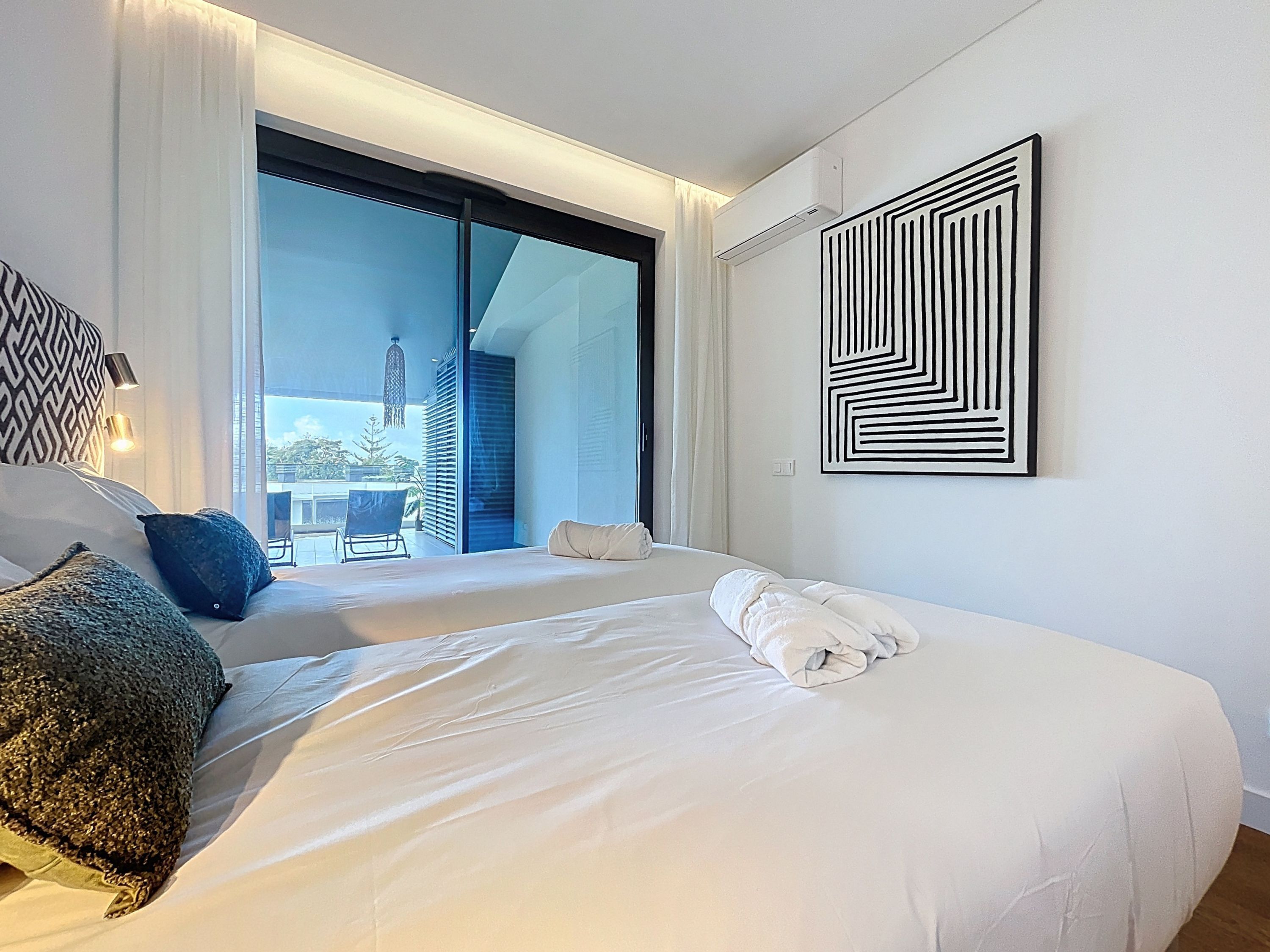 Ett modernt hotellrum med två sängar, ett stort fönster och utsikt över staden.