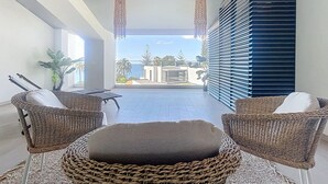A balcony with wicker furniture, a view of the ocean, and a building with blue shutters. - Acqua Beach by Atlantic Holiday (Funchal)