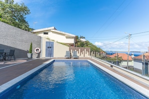 A swimming pool with lounge chairs, a lifebuoy, and a view of the sea. - Villa Alves by Atlantic Holiday (Santana)