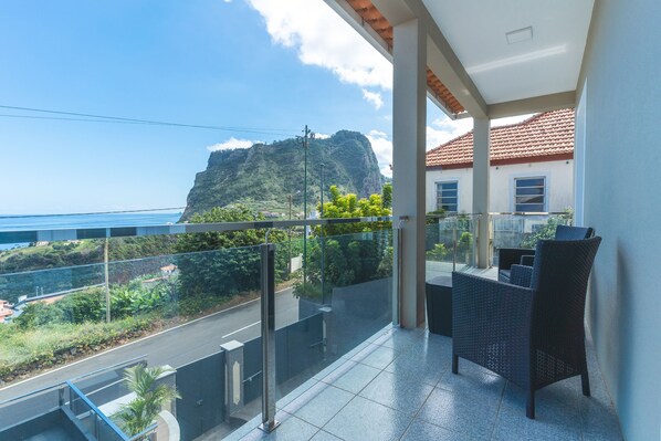 A balcony with a view of a mountain and the ocean.