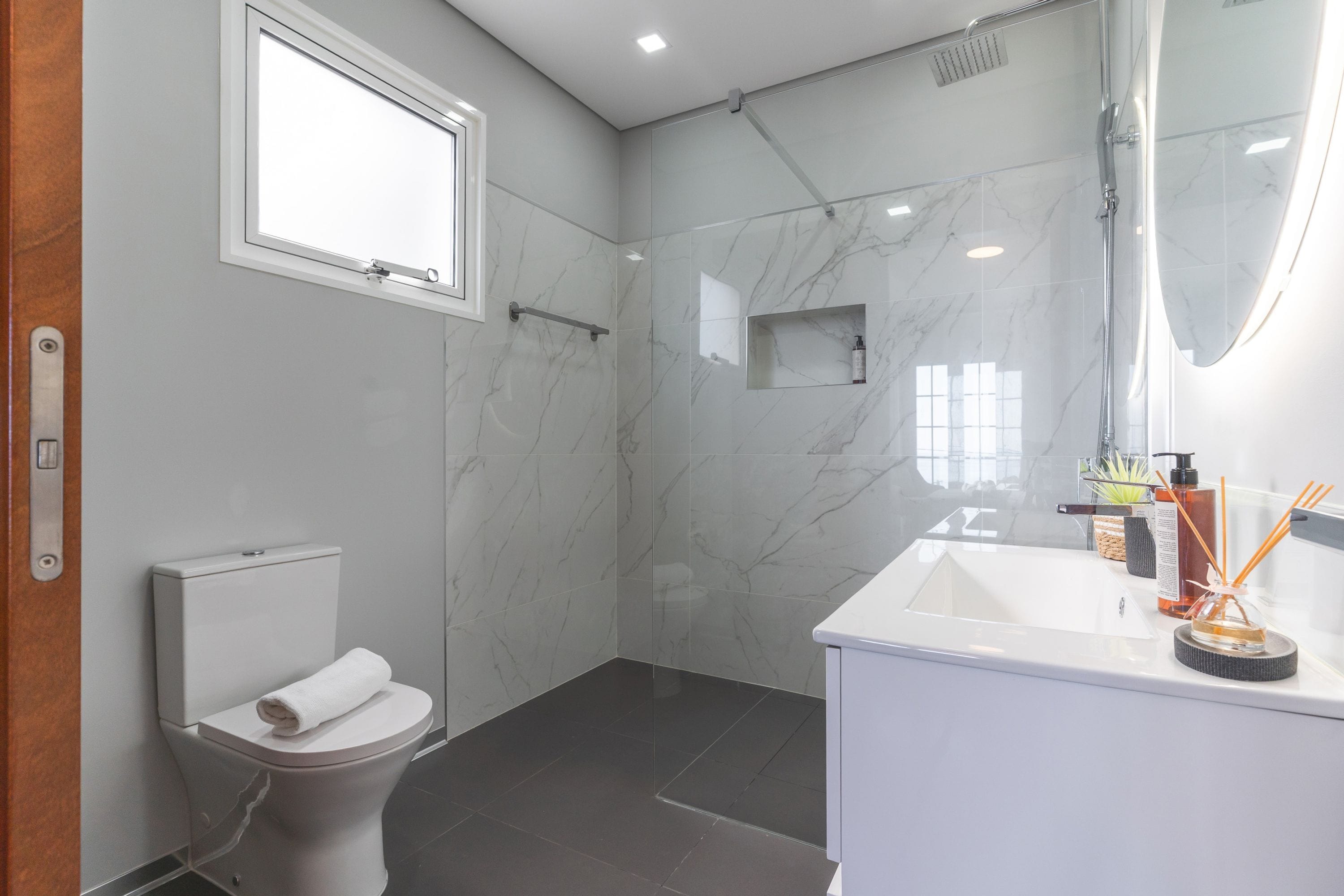 A modern bathroom with a toilet, shower, and sink.