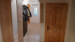 A hallway with a wooden wardrobe, a tiled floor, and a wooden door. - Apartment on a horse farm, children and pets welcome, garden & terrasse, grill (Lichtenau)
