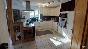 A modern kitchen with white cabinets, a wooden island, and a built-in oven. - Apartment on a horse farm, children and pets welcome, garden & terrasse, grill (Lichtenau)