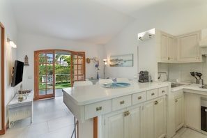 A kitchen with white cabinetry, a large island, and a dining area with a view of the outdoors.