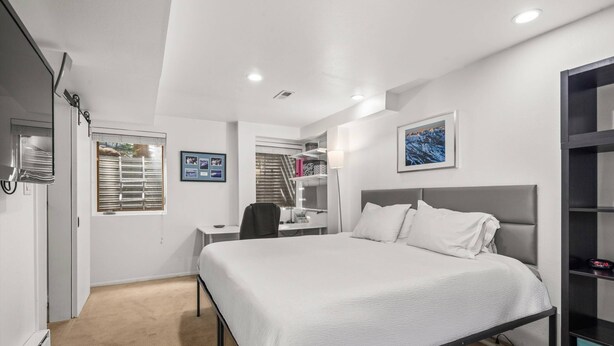 A modern hotel room with a large bed, a desk, and a chair. There is a window with blinds, a lamp, and a framed picture on the wall. - Aspen Villas/bleeker Street Townhome 2 Plus Den (Aspen)