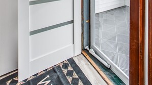 Una puerta blanca con listones horizontales y una puerta de vidrio con un picaporte de metal.