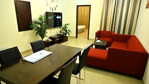 A modern living room with a wooden dining table, red sofa, and a TV mounted on the wall. - Aspire Tower (Manama)