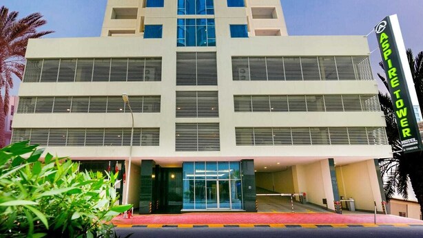 A tall hotel with a modern design, featuring a prominent entrance and a sign for Aspire Tower Hotel. - Aspire Tower (Manama)