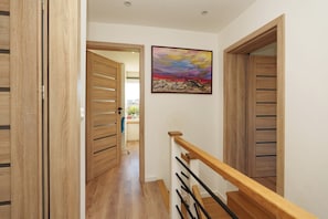 A wooden staircase with a handrail, a painting on the wall, and a door leading to another room.