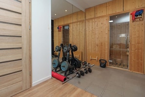 A gym with wooden walls, weightlifting equipment, and a tatami mat floor.