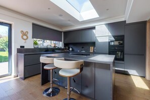 Una cocina moderna con una isla central, taburetes de bar y electrodomésticos integrados.