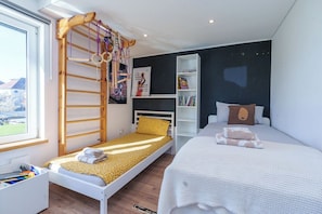 A bedroom with a bunk bed, a single bed, a bookshelf, and a window with a view. - Open Mind Property - Escape to the New Forest Edge (Southampton)
