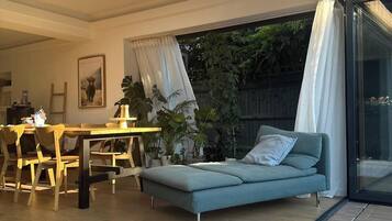 A modern interior with a dining area, a sofa, and a glass door leading to a garden.