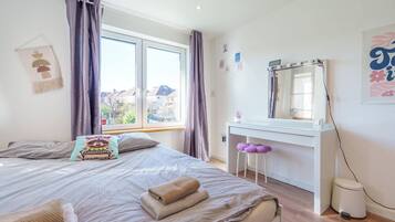 Une chambre à coucher avec un lit, un bureau, un miroir et une fenêtre.