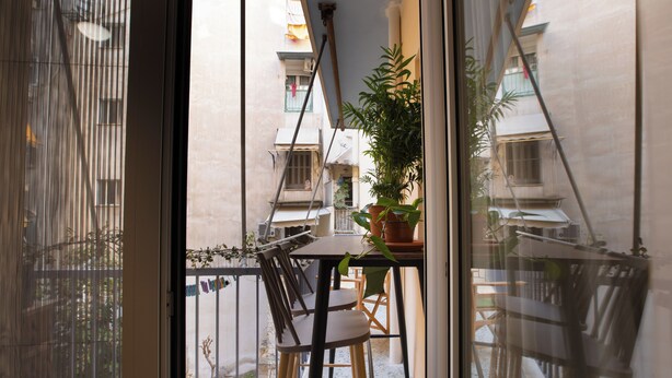 Ein Balkon mit Tisch, Stühlen und einem Blumentopf.