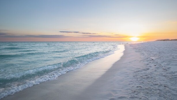 Une plage avec un coucher de soleil sur l’océan.
