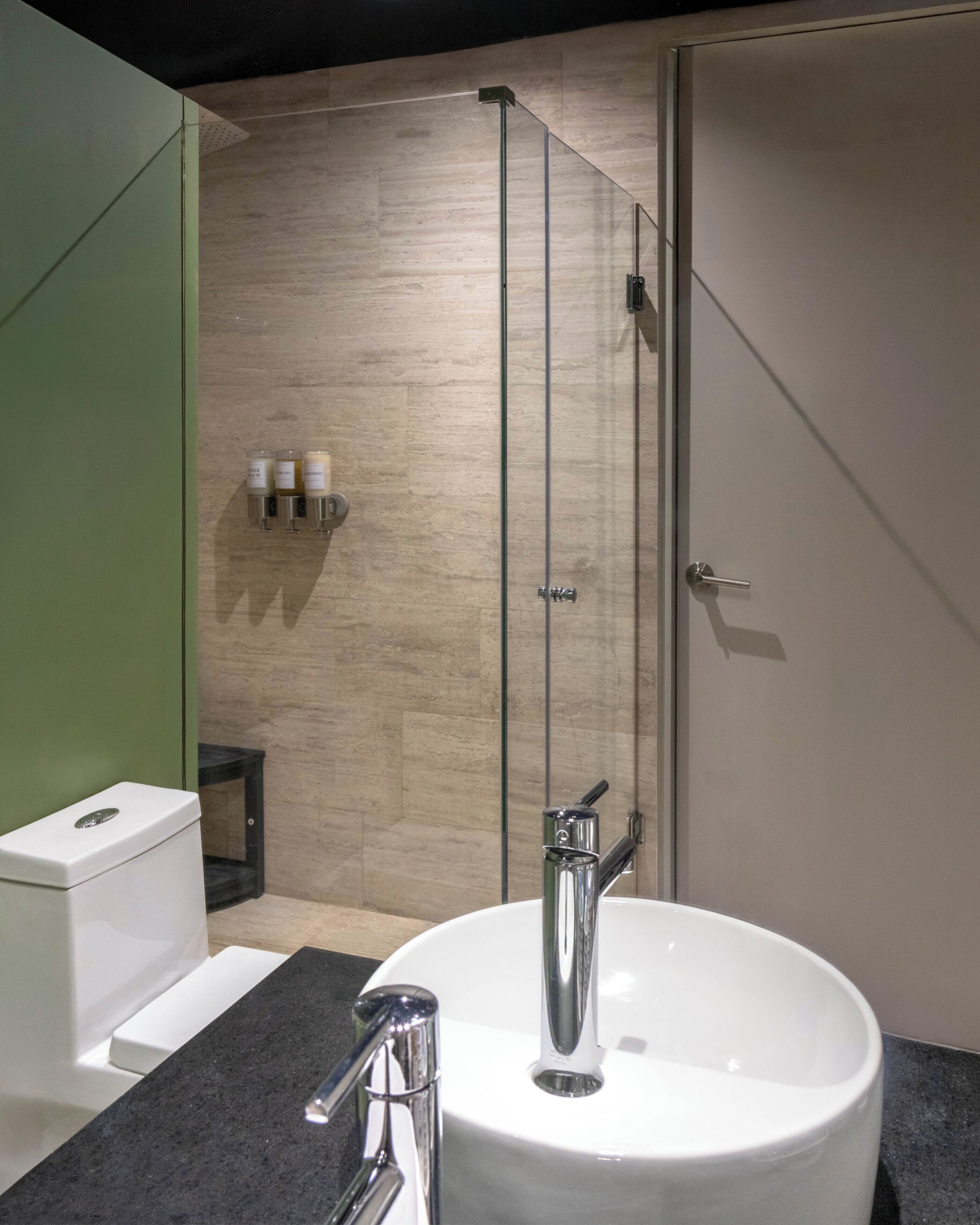 Un bany modern amb un rentapans blanc, aixeta cromada i una cabina de dutxa de vidre.